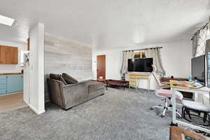 Office space featuring wooden walls, carpet, and a textured ceiling