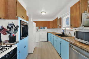 Kitchen featuring butcher block countertops, sink, stainless steel appliances, and independent washer and dryer