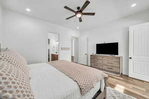 Bedroom with ensuite bathroom, ceiling fan, and light hardwood / wood-style floors