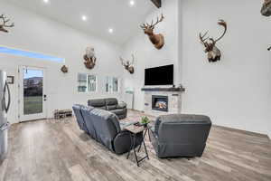 Living room with beamed ceiling, hardwood / wood-style floors, high vaulted ceiling, and a stone fireplace