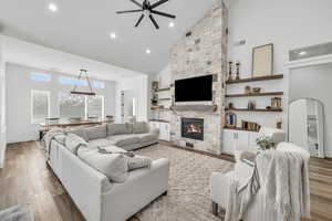 Living room with ceiling fan, wood-type flooring, a fireplace, and high vaulted ceiling