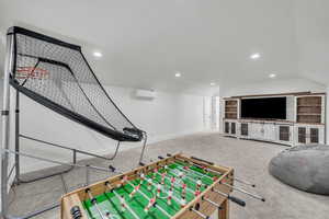 Game room featuring carpet floors, a wall mounted AC, and lofted ceiling