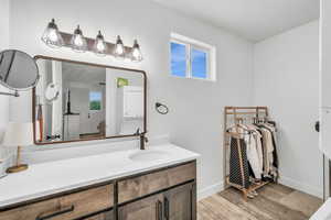 Bathroom featuring hardwood / wood-style floors, vanity, a healthy amount of sunlight, and stacked washer / drying machine