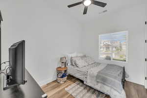 Bedroom with ceiling fan, hardwood / wood-style floors, and lofted ceiling