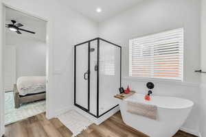 Bathroom featuring ceiling fan, wood-type flooring, and shower with separate bathtub