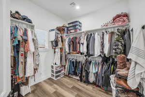 Walk in closet with hardwood / wood-style floors