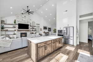 Kitchen featuring white cabinetry, a center island, stainless steel appliances, high vaulted ceiling, and wood-type flooring