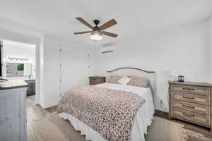 Bedroom with a wall unit AC, ceiling fan, hardwood / wood-style flooring, connected bathroom, and a closet