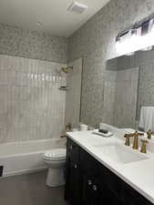 Full bathroom featuring tile patterned flooring, tiled shower / bath combo, toilet, and vanity