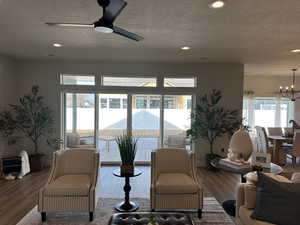 Living room with hardwood / wood-style floors, ceiling fan with notable chandelier, and a textured ceiling