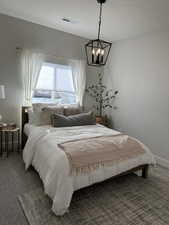 Carpeted bedroom featuring an inviting chandelier