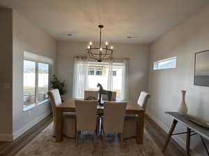 Dining space featuring a textured ceiling, a notable chandelier, a healthy amount of sunlight, and dark wood-type flooring