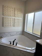 Bathroom featuring vanity and tiled tub