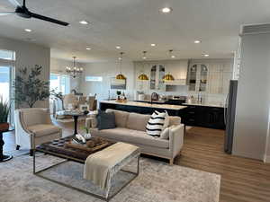 Living room with a textured ceiling, ceiling fan with notable chandelier, light hardwood / wood-style floors, and sink