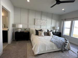 Carpeted bedroom featuring ensuite bath and ceiling fan