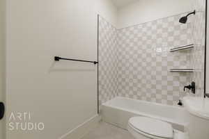 Bathroom with tile patterned flooring, toilet, and tiled shower / bath