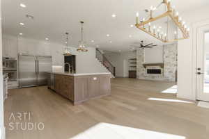 Kitchen featuring ceiling fan, a large island, a fireplace, white cabinets, and appliances with stainless steel finishes