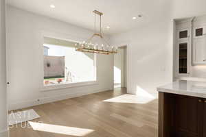 Unfurnished dining area with a notable chandelier and light wood-type flooring