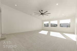 Carpeted empty room with ceiling fan and lofted ceiling