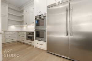 Kitchen with backsplash, light hardwood / wood-style flooring, white cabinets, and appliances with stainless steel finishes