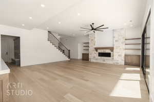 Unfurnished living room with a stone fireplace, ceiling fan, and light hardwood / wood-style flooring