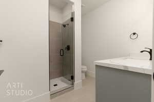 Bathroom featuring tile patterned floors, vanity, toilet, and a shower with shower door