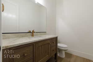 Bathroom with hardwood / wood-style floors, vanity, and toilet