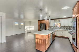 Kitchen featuring sink, stainless steel appliances, backsplash, pendant lighting, and a kitchen island with sink