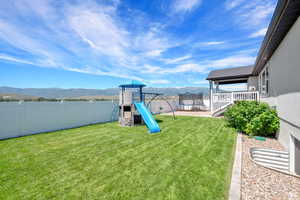 View of play area with a lawn, a mountain view, and a trampoline