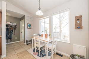 Dining space featuring light tile patterned floors and vaulted ceiling