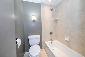 Full bath featuring toilet, bathing tub / shower combination, and baseboards