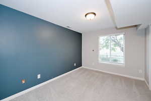 Empty room with baseboards and light colored carpet