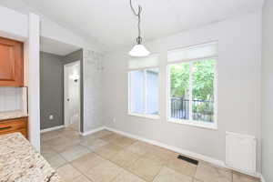 Unfurnished dining area with vaulted ceiling, light tile patterned floors, and baseboards