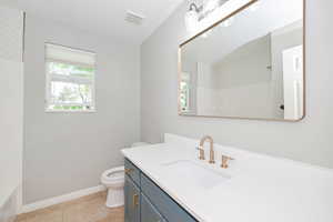 Full bath with toilet, baseboards, vanity, and a shower