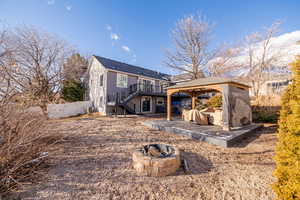 Back of house with a gazebo, a wooden deck, and a fire pit