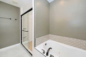 Full bath with a whirlpool tub, a stall shower, marble finish floors, and baseboards