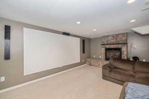 Cinema room with carpet, a fireplace, and a textured ceiling