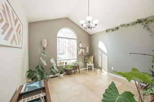 Sitting room with an inviting chandelier, light tile patterned floors, and vaulted ceiling