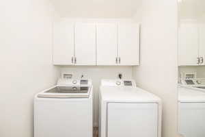 Washroom featuring cabinets and independent washer and dryer