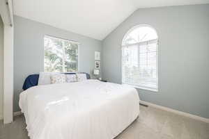 Bedroom with lofted ceiling and light carpet