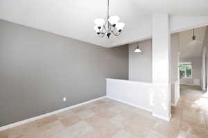 Unfurnished room with a chandelier, lofted ceiling, light tile patterned flooring, and baseboards