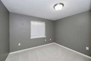 Empty room featuring carpet and baseboards