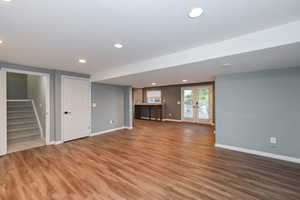 Unfurnished living room featuring baseboards, light wood-type flooring, stairway, recessed lighting, and french doors