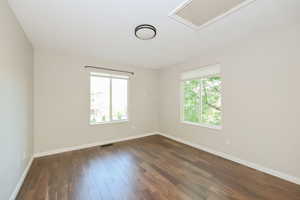 Spare room featuring plenty of natural light, baseboards, and dark wood-style floors
