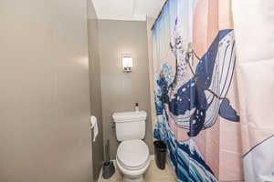 Bathroom featuring tile patterned flooring, toilet, and a shower with shower curtain