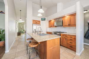 Kitchen featuring stainless steel appliances, sink, a center island with sink, high vaulted ceiling, and hanging light fixtures