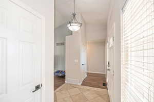 Hall with light tile patterned floors and vaulted ceiling