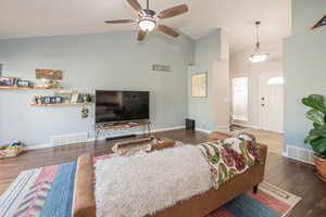 Living room with ceiling fan, high vaulted ceiling, and dark wood-type flooring