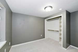 Unfurnished bedroom featuring carpet flooring, baseboards, and a closet