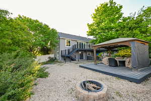 Rear view of property featuring an outdoor fire pit, a gazebo, stairway, a deck, and fence